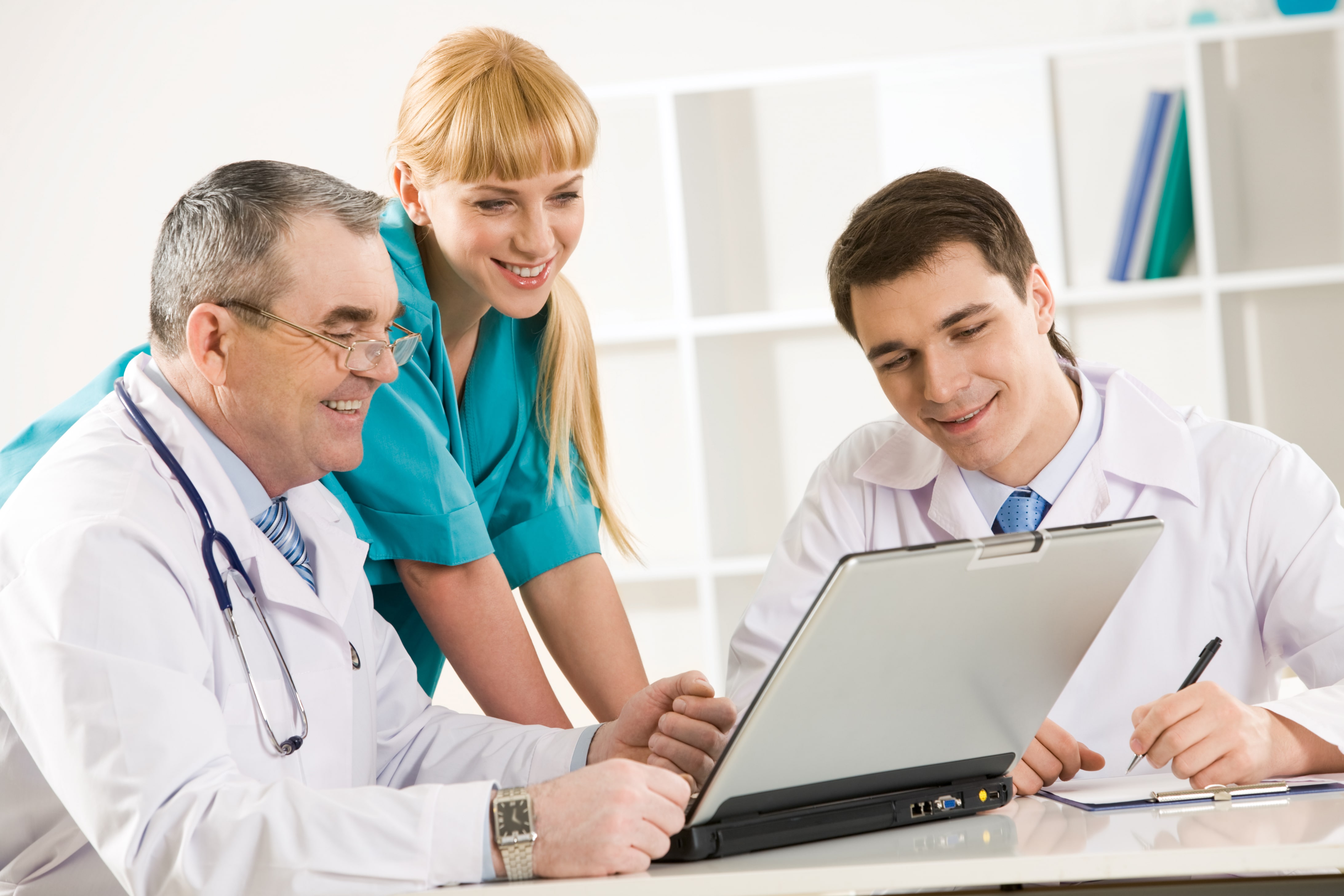 Group of healthcare providers discussing the staff scheduling, looking at Shiftboard on laptop