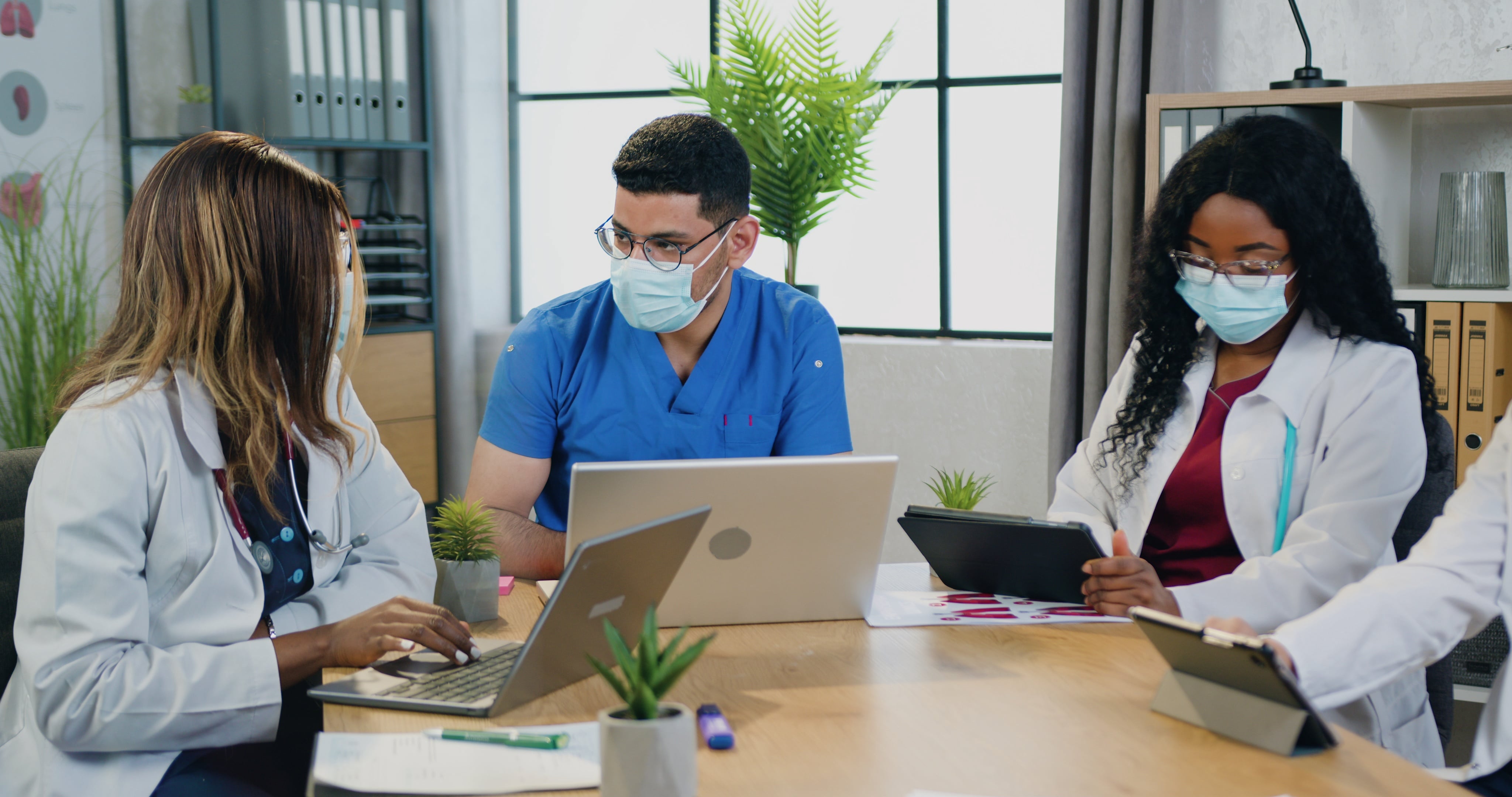 Masked healthcare workers in meeting looking over the work schedule